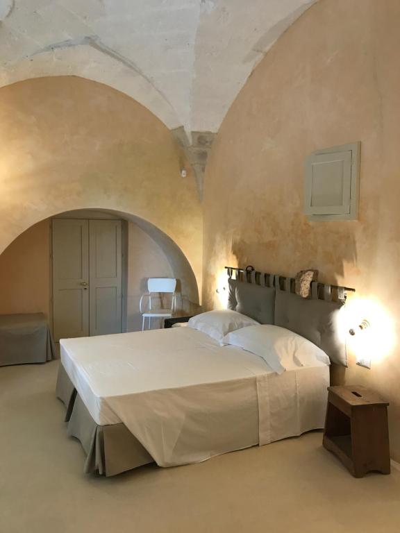 库特罗菲安诺Tenuta Castelle的卧室配有一张带两个拱门的大型白色床