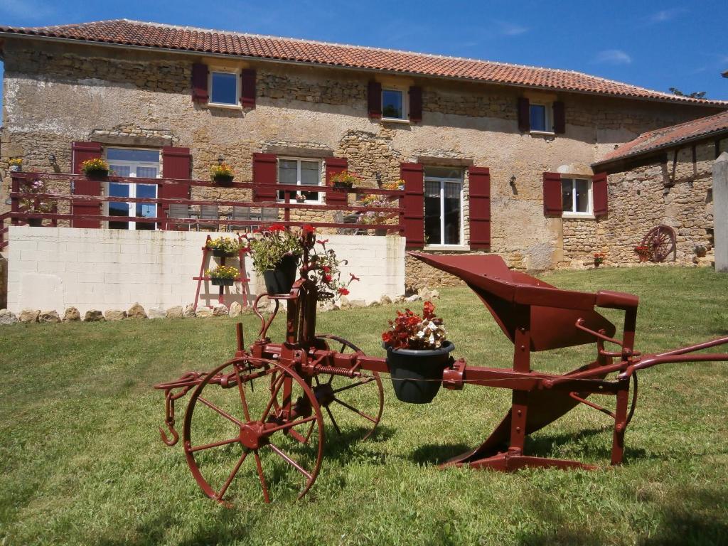 Saint-Médard-de-Presque绍米尔德住宿加早餐旅馆的建筑前的院子内装有鲜花的红色拖拉机