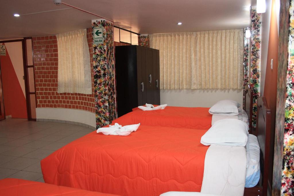 卡哈马卡Hotel Los Gladiolos的配有红色床单和白色毯子的客房内的两张床