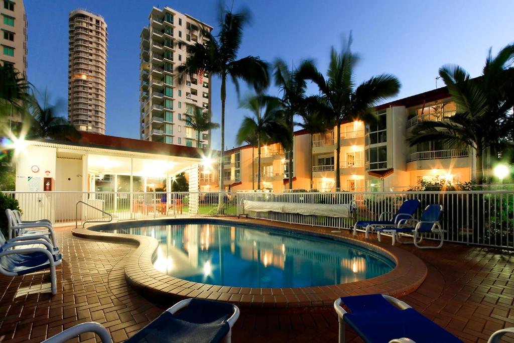 黄金海岸基拉戈假日公寓酒店的一座带椅子的游泳池以及一座建筑