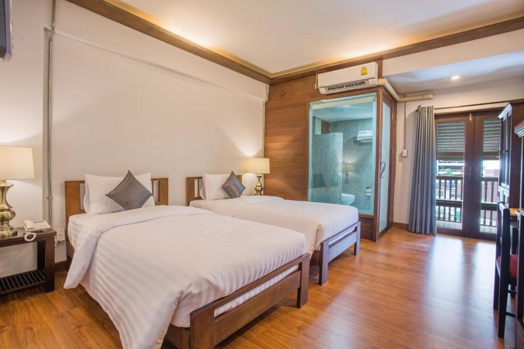 清迈夜市酒店的铺有木地板的客房内的两张床