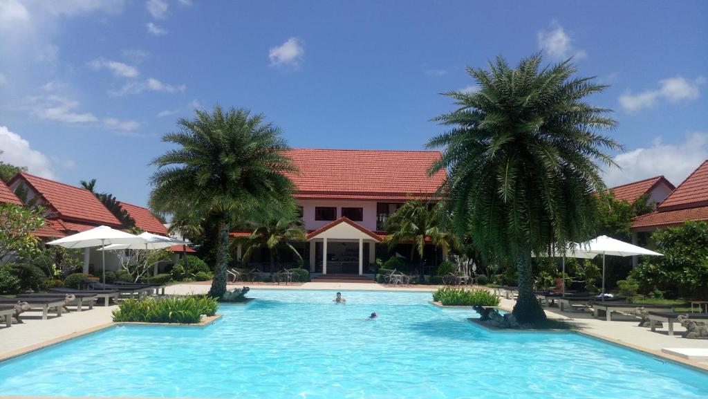 春蓬阿尔莫尼亚乡村Spa度假酒店的一座建筑前的游泳池,两棵棕榈树