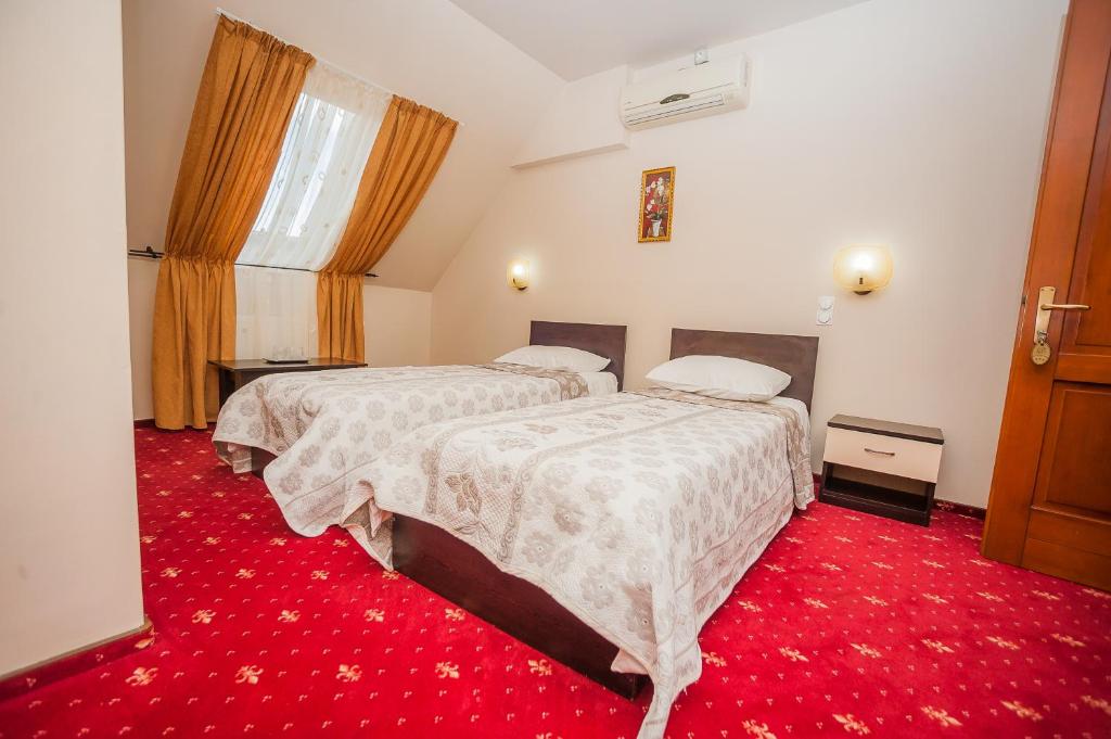 比斯特里察Vila Romance的酒店客房,设有两张床,铺有红地毯。