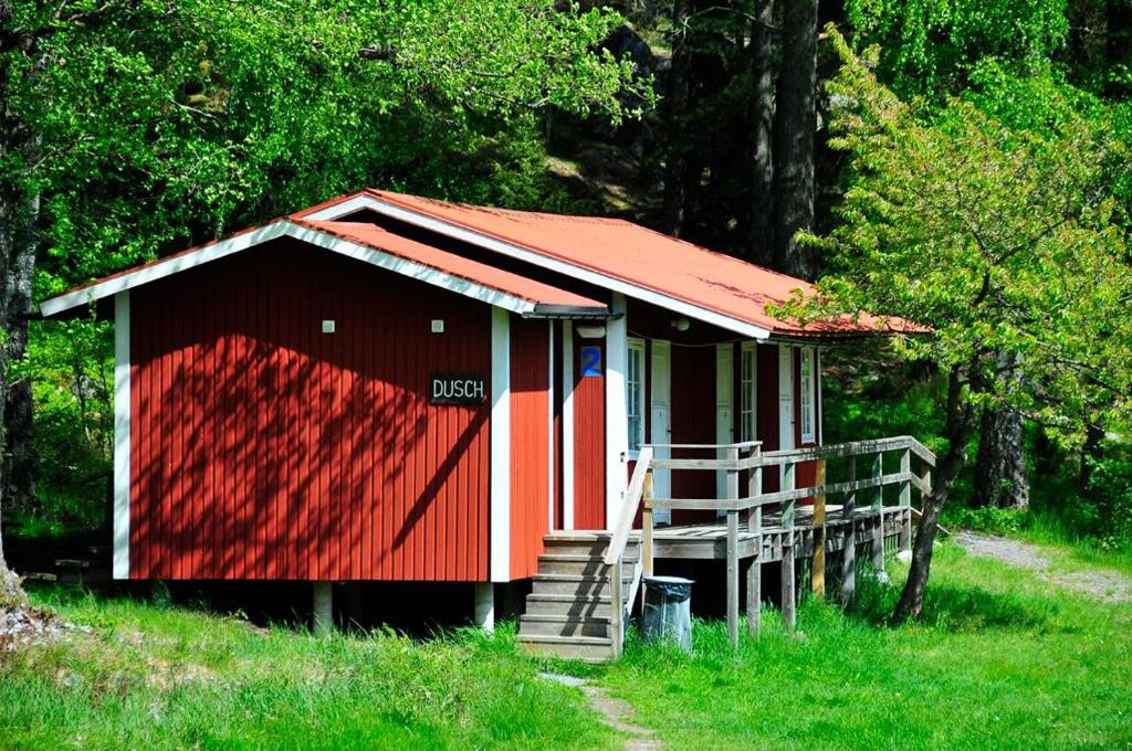 格林达Grinda Stugby och Sea Lodge - Pensionat med kost & logi的一块红色和白色的棚子,在田野上有一个楼梯