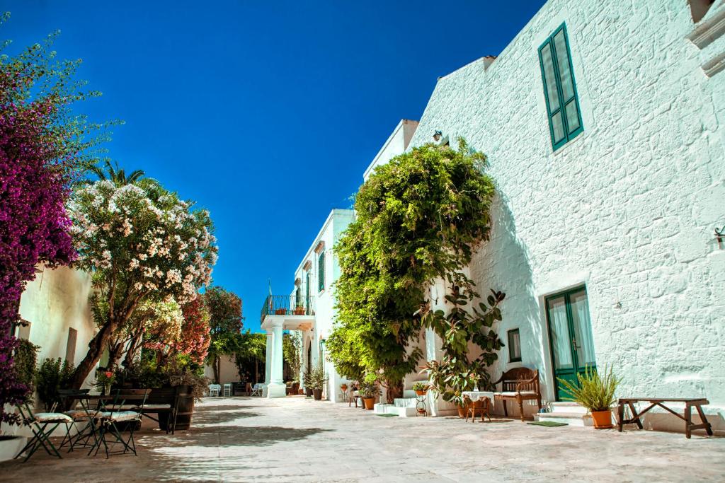 奥斯图尼玛西里雅伊尔法兰托依欧酒店的白色建筑的庭院,有桌子和树木