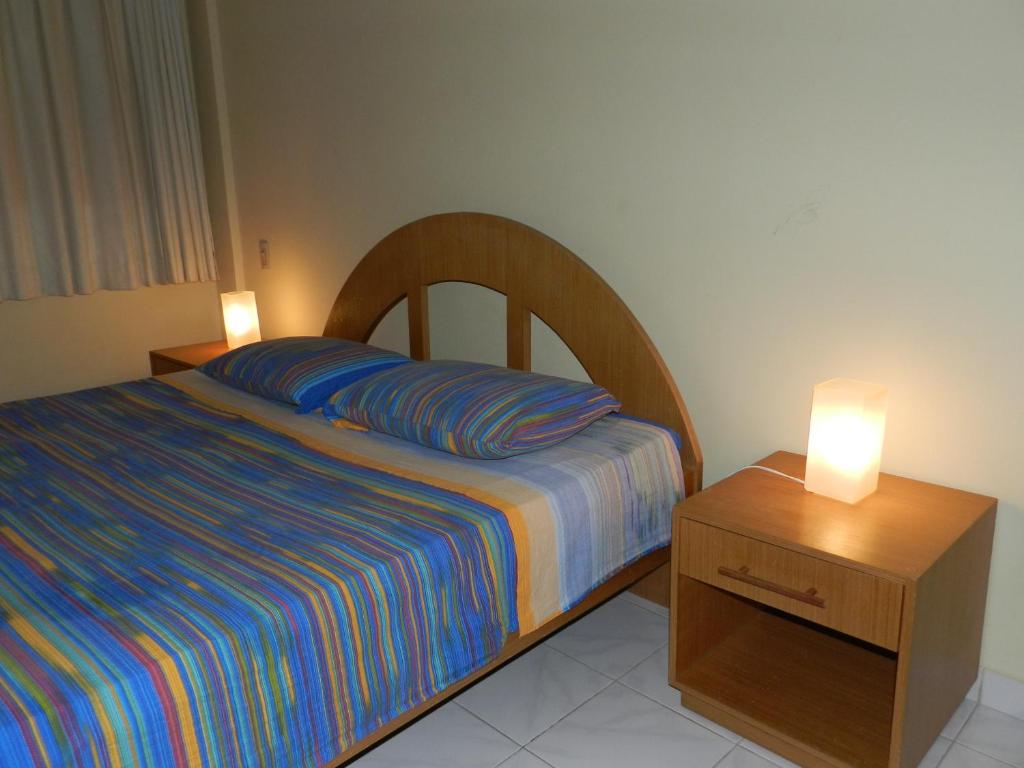 纳塔尔艾颇雷蒂亚公寓酒店的一间卧室配有一张床和一个带两盏灯的床头柜。