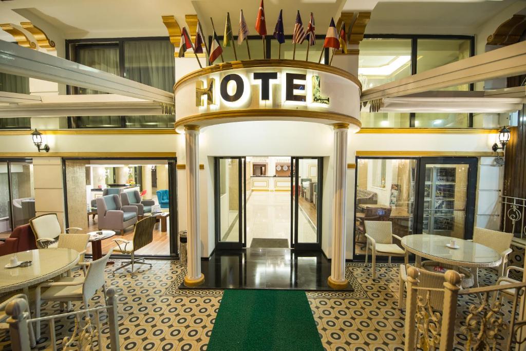 伯萨Ruba Palace Thermal Hotel的酒店大堂设有桌椅和酒店标志