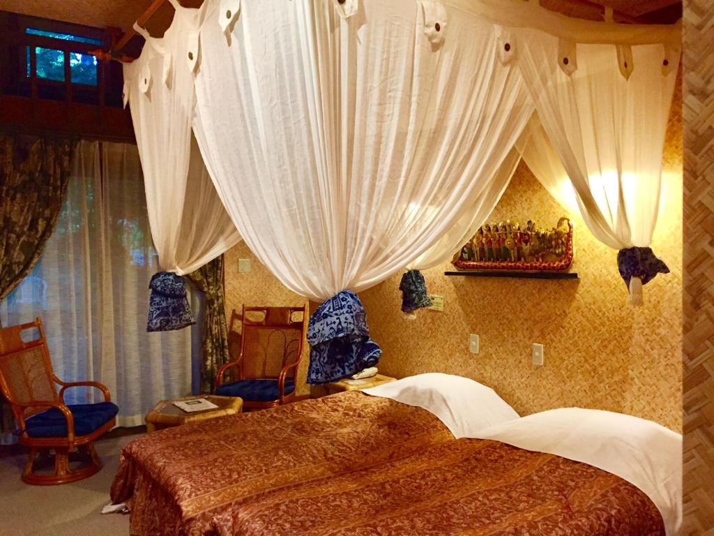 嬬恋村埃斯蒂万特俱乐部旅馆的一间卧室配有床、窗帘和椅子