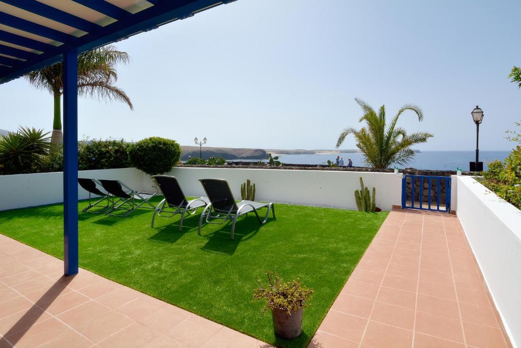 普拉亚布兰卡Villa Vista Mar的庭院配有椅子,草坪则以大海为背景