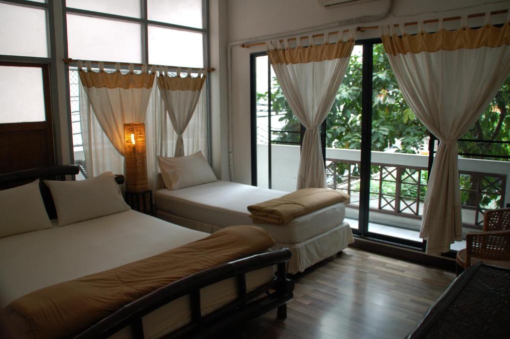 曼谷Lamphuhouse Bangkok - SHA Extra Plus Certified的一间卧室设有两张床、一把椅子和窗户。
