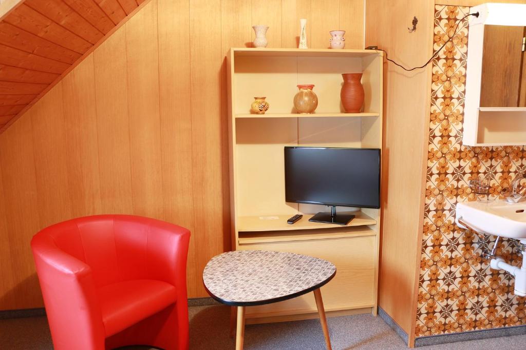 圣加仑布莱姆餐厅旅馆的一间设有红色椅子和电视的房间
