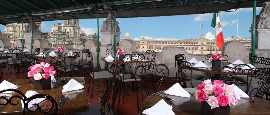墨西哥城贝斯维斯特大华酒店的一间设有桌椅的餐厅,享有城市美景