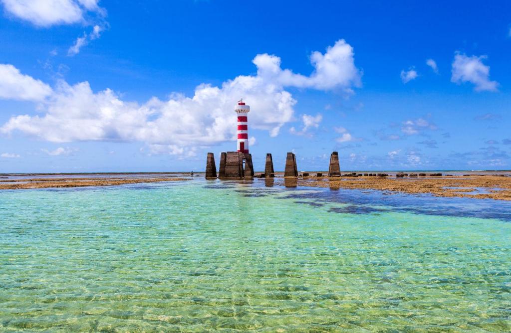 马塞约Sun Paradise - Pio X的海滩旁的水中的一个红白色灯塔