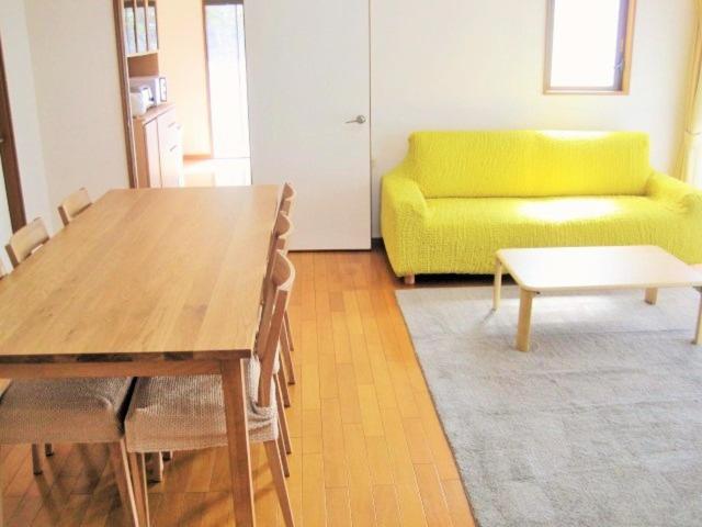 立山町果菜园厨房旅馆的客厅配有桌子和黄色沙发