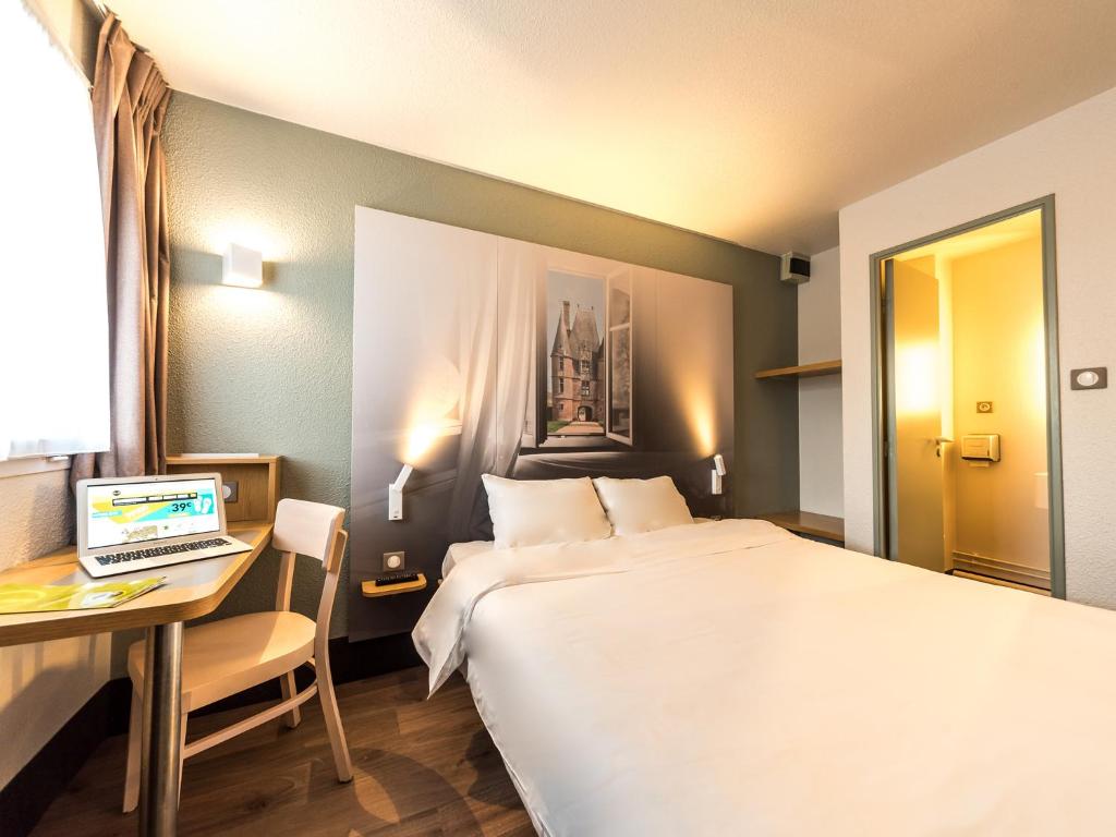 阿朗松B&B HOTEL Alencon Nord的酒店客房配有一张床、一张书桌和一台笔记本电脑
