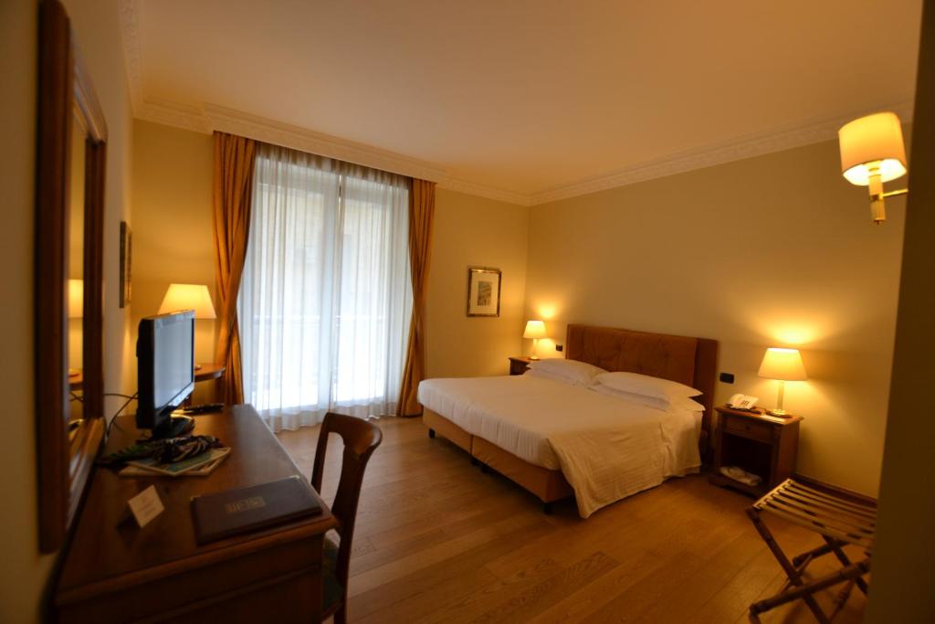 卡塔尼亚卡塔奈宫酒店的酒店客房配有一张床和一张书桌及一台电视