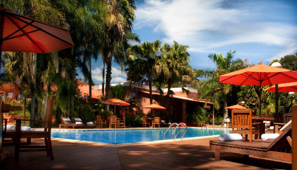 伊瓜苏港Orquideas Hotel & Cabañas的一个带椅子和遮阳伞的度假游泳池