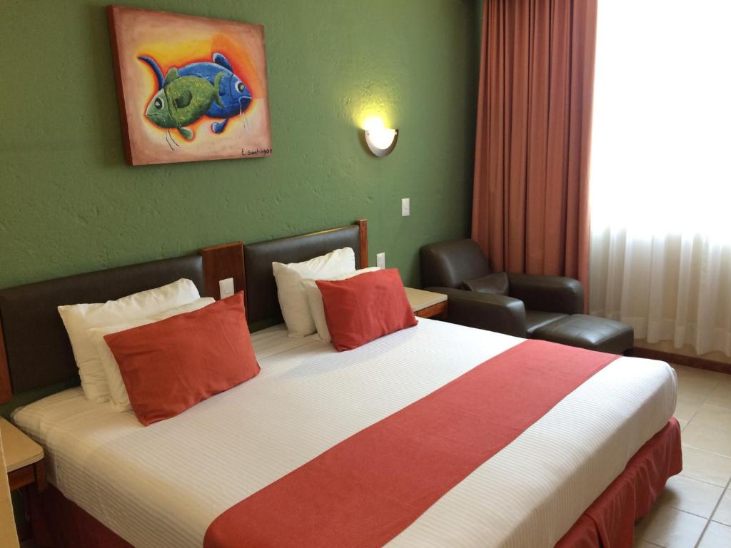 夸察夸尔科斯Hotel Enriquez的酒店客房配有一张带红色枕头的大床