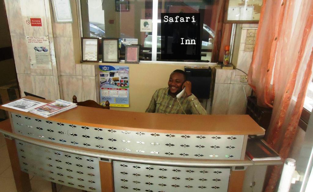 达累斯萨拉姆Safari Inn的一名男子在柜台后面的手机上讲话
