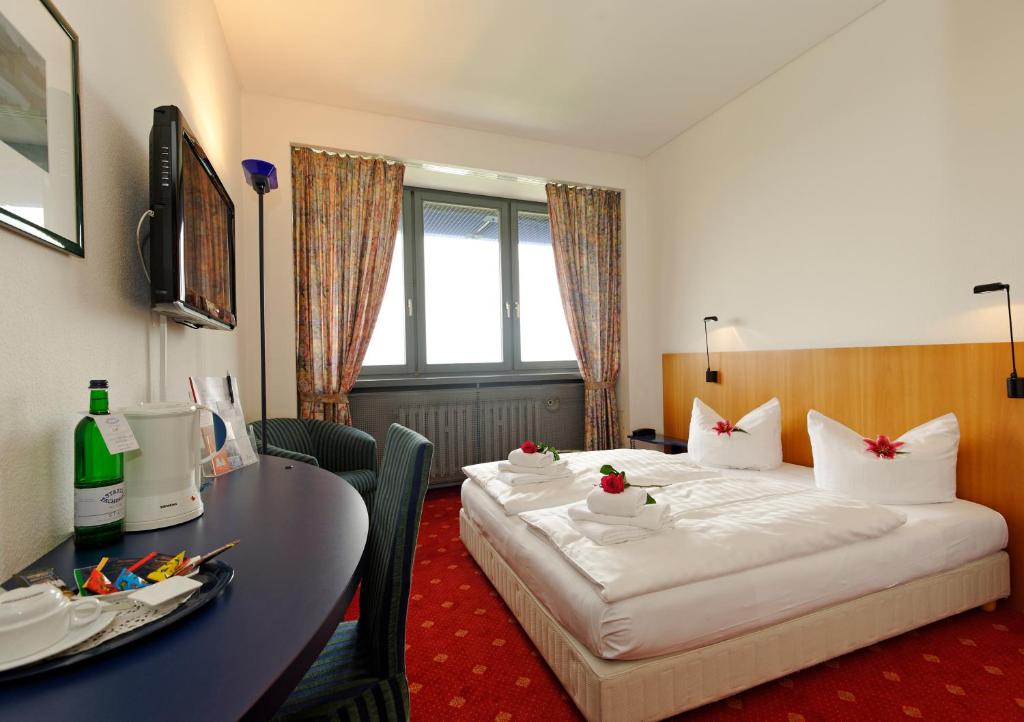 爱尔福特慕尼黑卡丽酒店的酒店客房设有两张床和一张桌子。