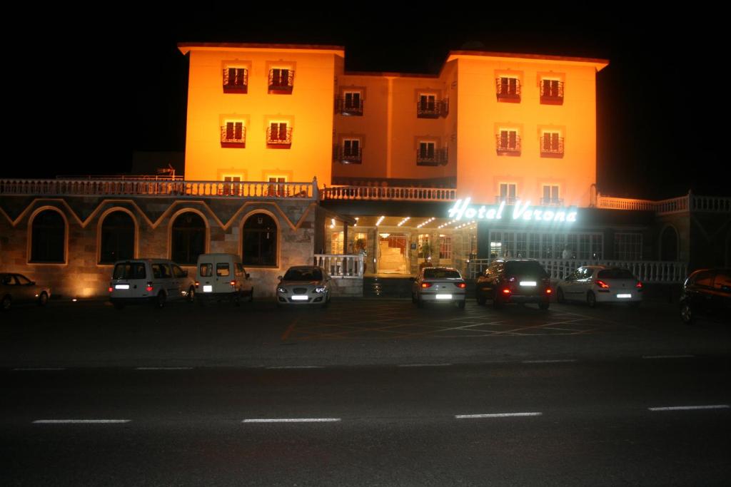 普埃托利亚诺维洛拉酒店的一座有汽车在晚上停在停车场的建筑