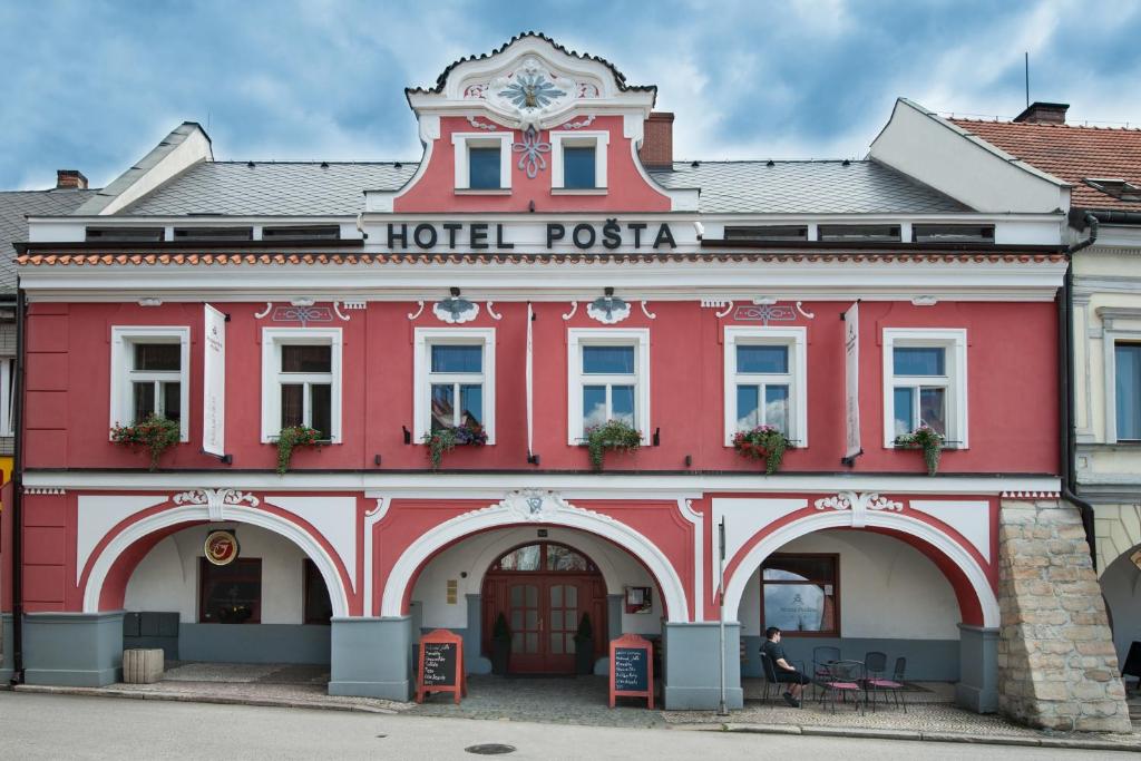 索博特卡Hotel Pošta的一座红色的建筑,上面有酒店的比萨