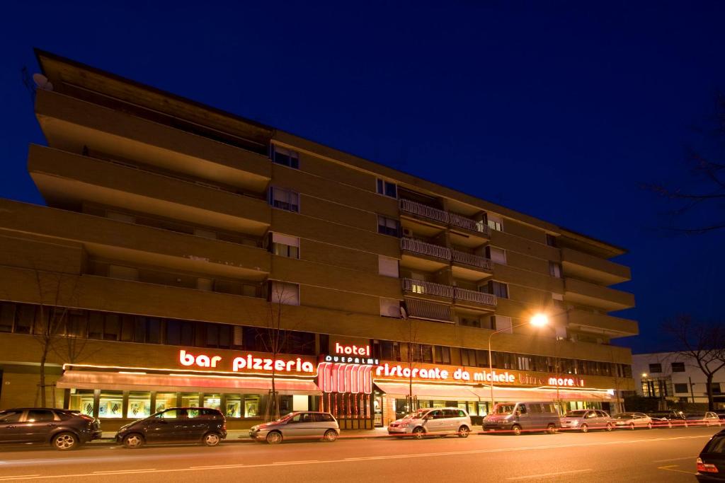乌迪内奥勒杜伊帕尔梅酒店的一座建筑,晚上有汽车停在外面