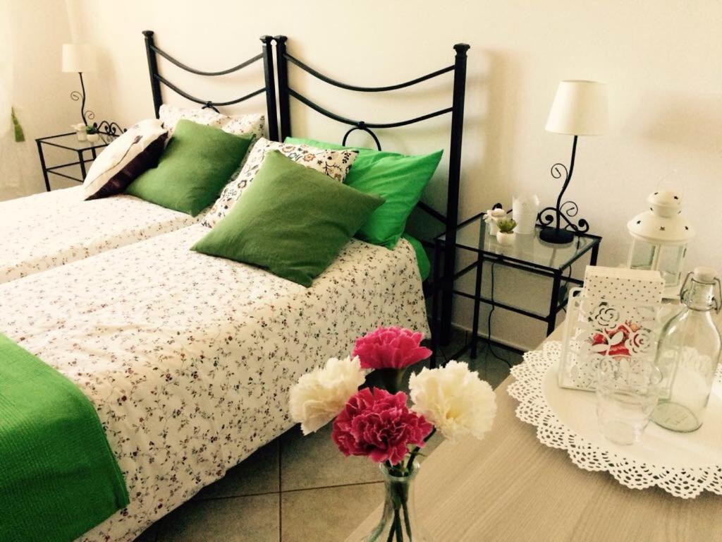 诺切劳恩布拉Appartamenti Monte Alago的一张带绿色粉色枕头的床和一张带鲜花的桌子