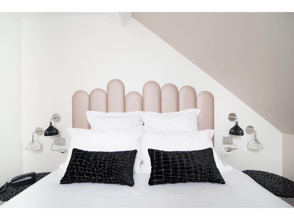 贝尔福卷尾猴餐厅酒店的卧室配有白色的床和黑白色枕头