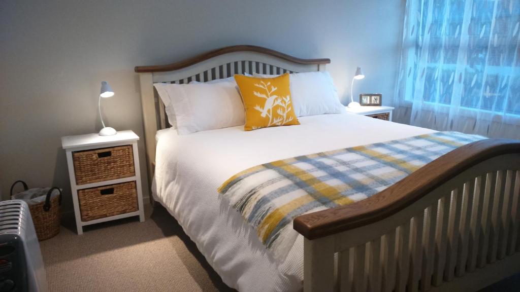 但尼丁Restview的一间卧室配有一张带黄色枕头和两盏灯的床