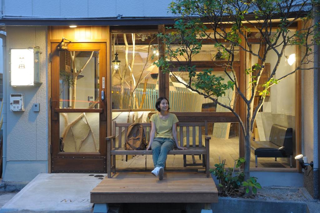 神户玛雅神户旅馆的坐在房子长凳上的女人