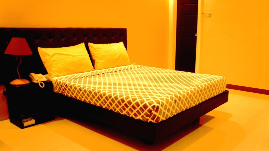 卢塞纳城市酒店的一间卧室配有一张黄色墙壁和一盏灯的床