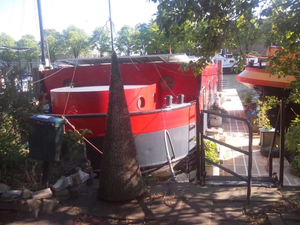 阿姆斯特丹Houseboat Dokstroom的停在树旁的红白船