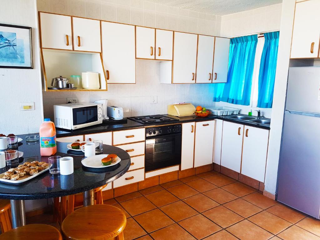 马盖特Dumela Margate Flat No 31的厨房配有白色橱柜和黑色台面
