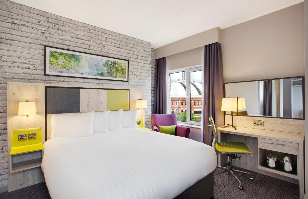 曼彻斯特Leonardo Hotel Manchester Central的酒店客房设有一张大床和一张书桌。
