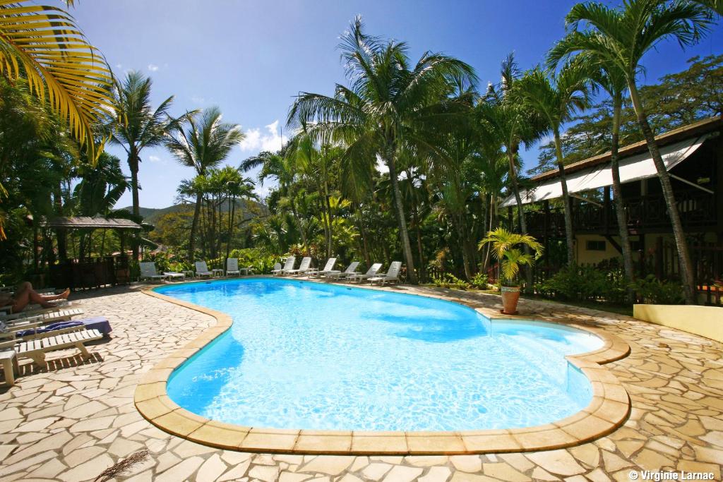 德赛Hotel - Résidence Habitation Grande Anse的一个带椅子和棕榈树的度假村游泳池
