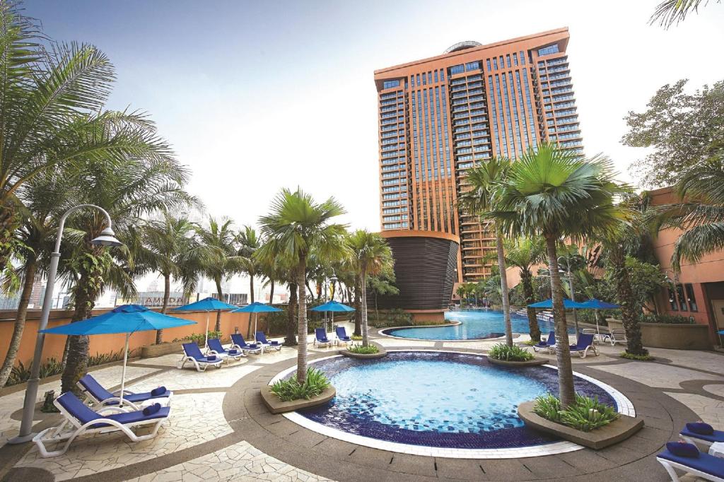 吉隆坡Berjaya Times Square Hotel, Kuala Lumpur的一座带椅子和棕榈树的游泳池以及一座高大的建筑