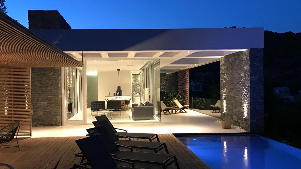 普洛马里翁A - Luxury Villas的一个带椅子的庭院和夜间游泳池