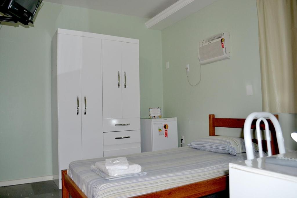 马卡埃Pousada Alto Riviera的一间带床和冰箱的小卧室