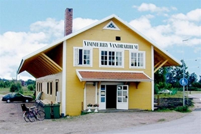 维默比Vimmerby Vandrarhem的黄色的建筑,上面有读到原始河道的标志
