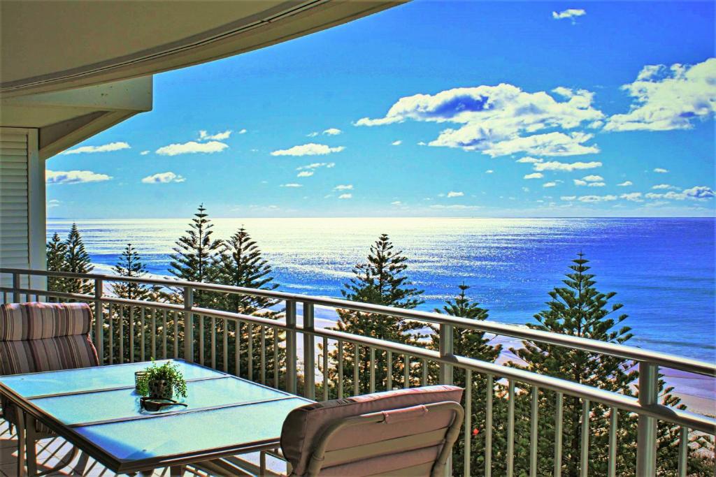 黄金海岸因迪格蓝色公寓式酒店的阳台配有桌子,享有海景。