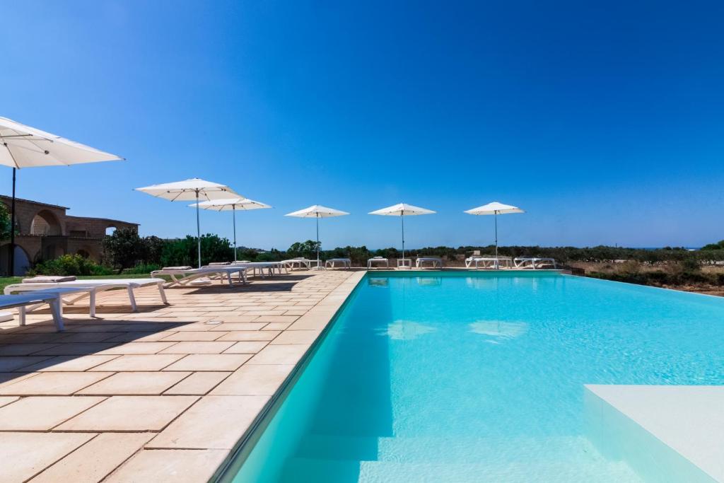 莱乌卡Montiro' Hotel的一个带遮阳伞和桌椅的游泳池
