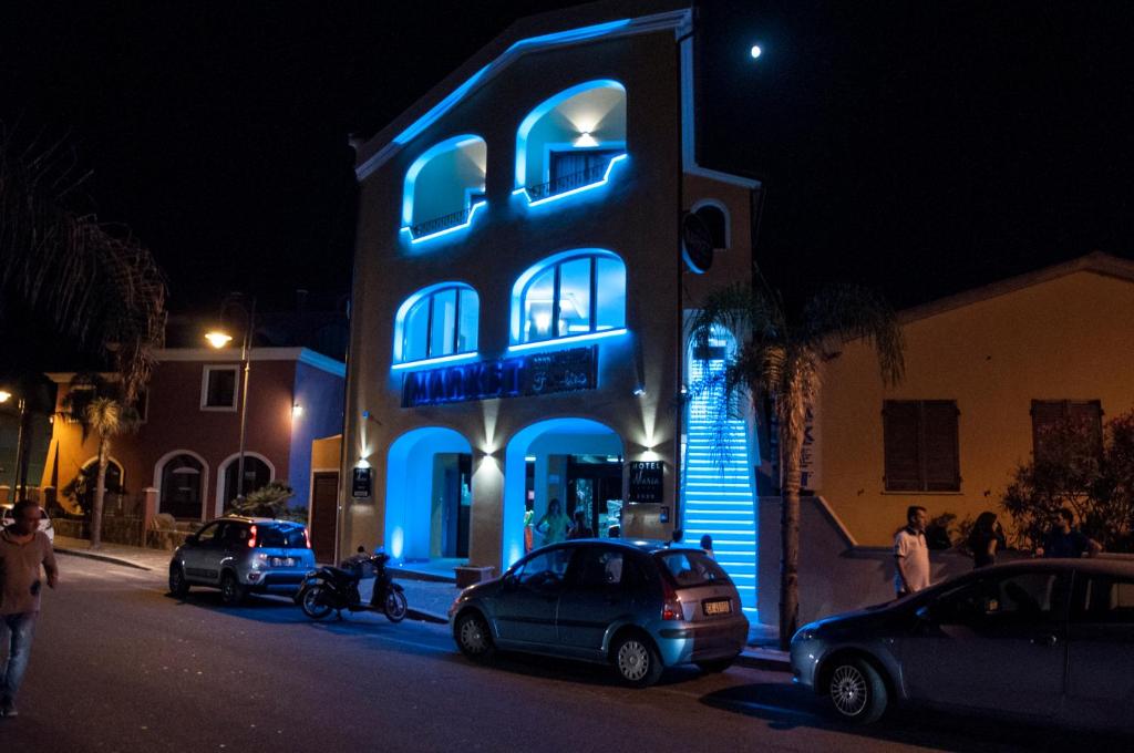 阿兰奇湾城玛丽亚酒店的一座蓝色的建筑,前面有汽车停放