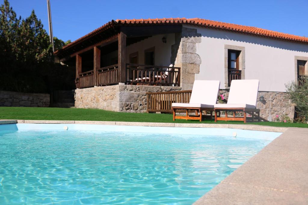 Vilarinho da CastanheiraCasa Dona Urraca的一座带游泳池和两把白色椅子的房子