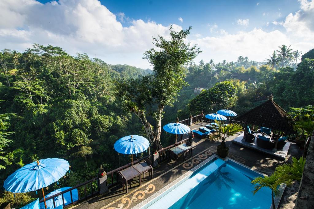 乌布Villa Kalisat Resort的享有带遮阳伞的度假村游泳池的景色