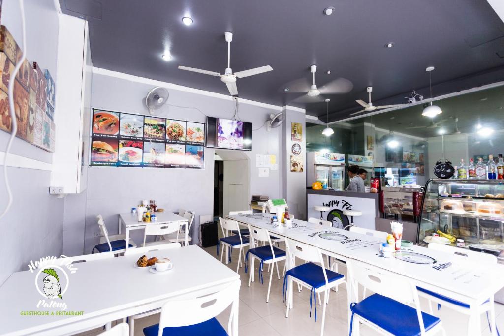 芭东海滩快乐鱼儿宾馆的餐厅设有白色的桌子和蓝色的椅子