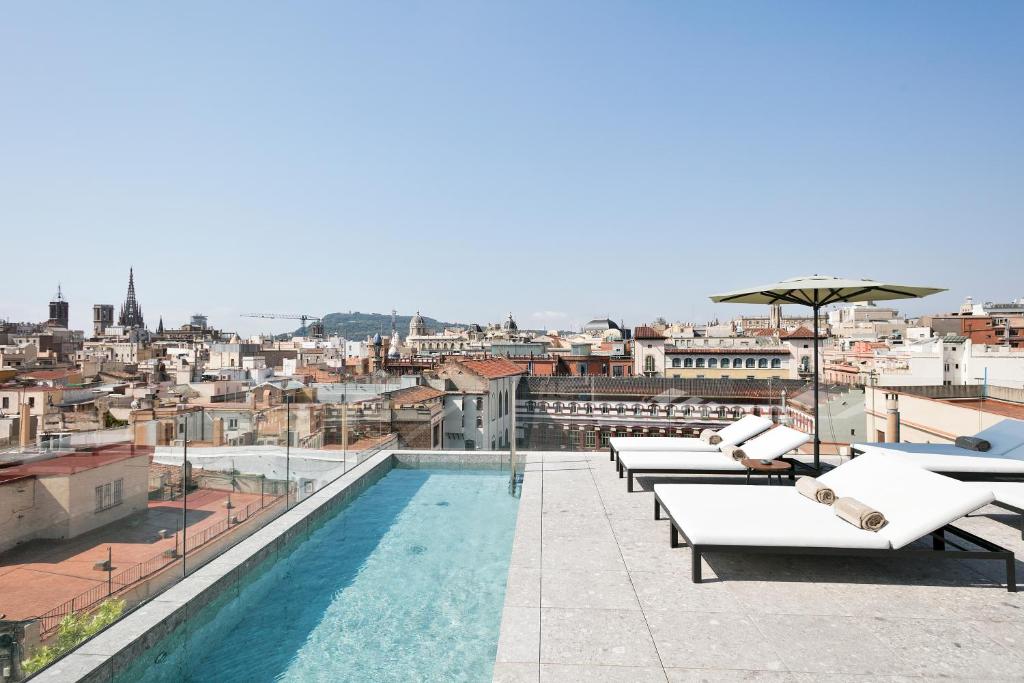 巴塞罗那约尔班帕萨基Spa酒店的一座带躺椅的建筑屋顶上的游泳池