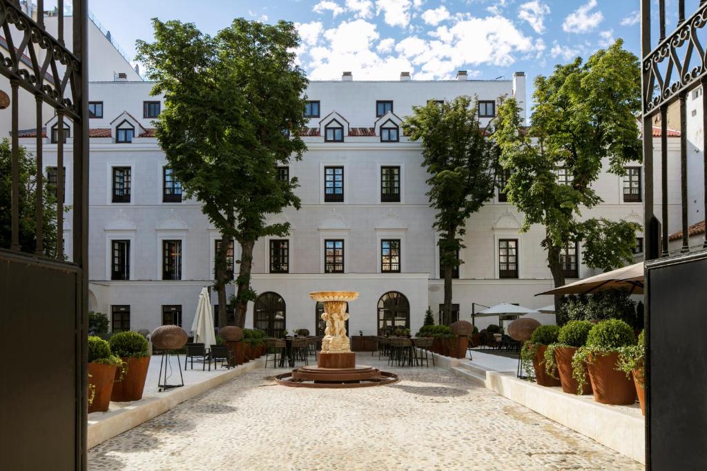 马德里Palacio de los Duques Gran Meliá - The Leading Hotels of the World的白色建筑前的庭院,带喷泉