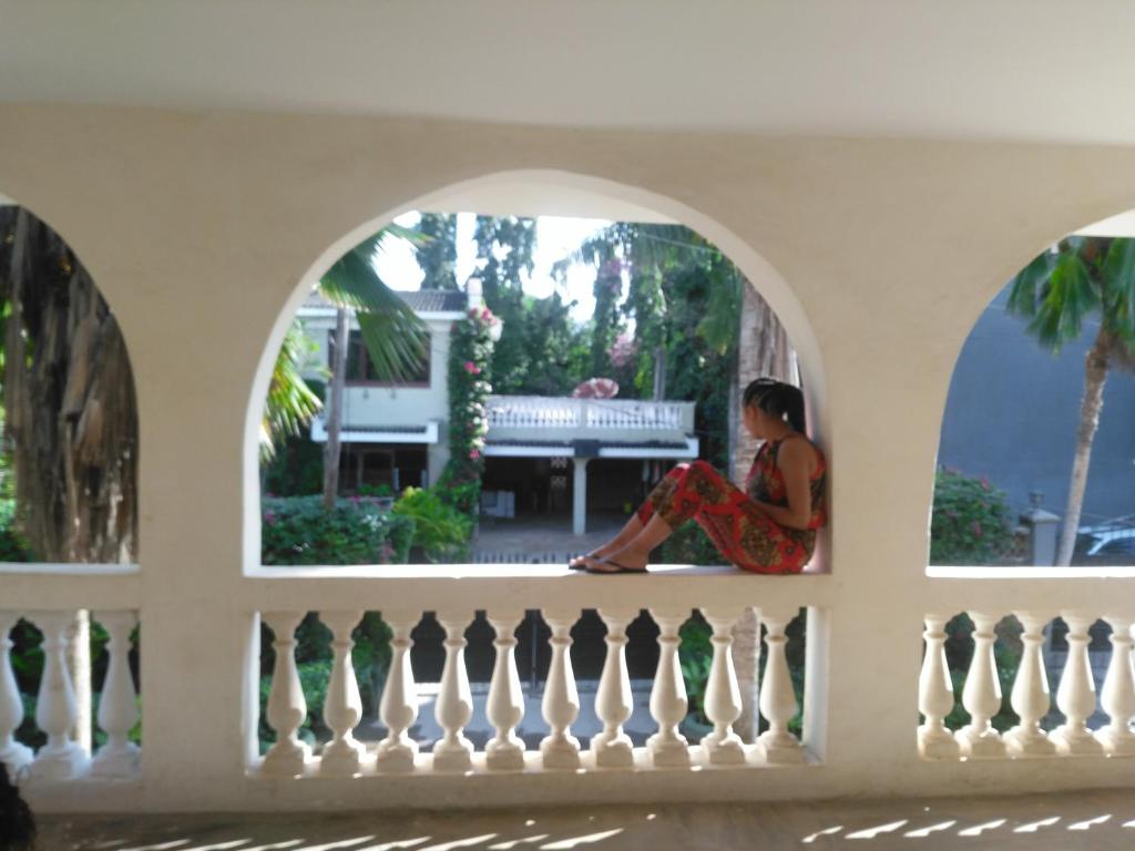 蒙巴萨Akogo House - Hostel and Backpackers的坐在窗外阳台的女人