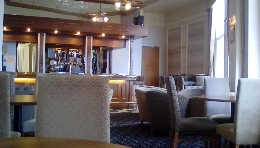 道格拉斯海德罗酒店的一间餐厅设有椅子,酒吧位于酒店后面